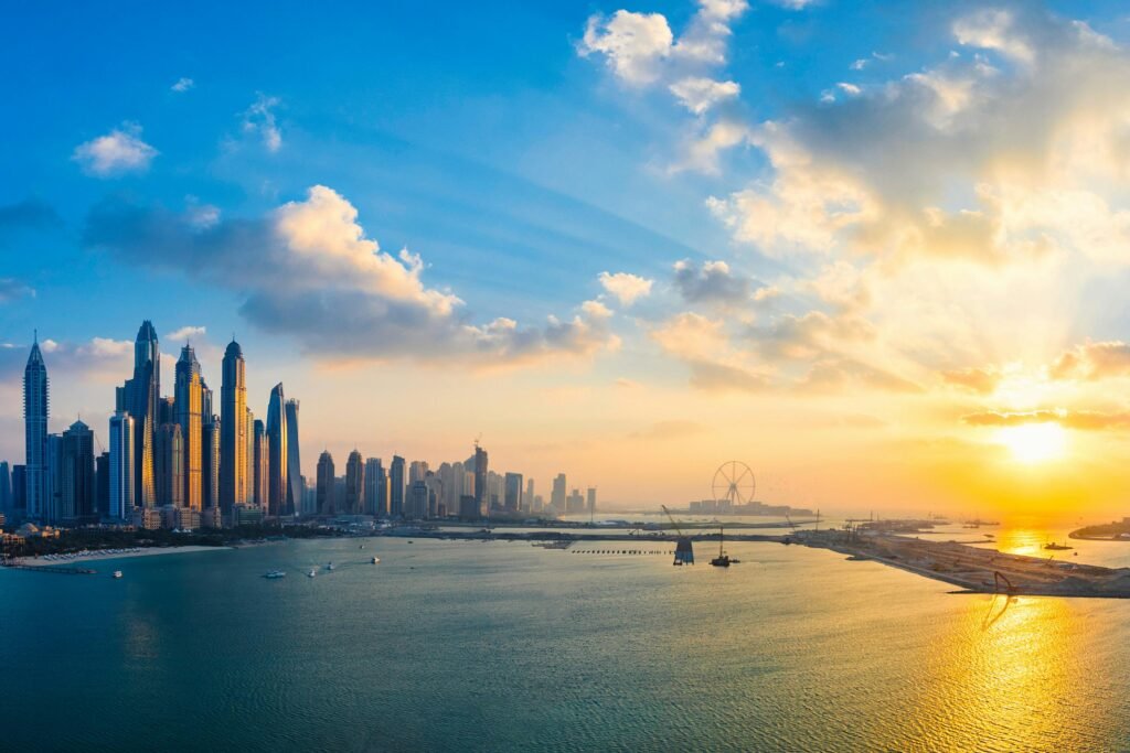 Stunning view of Dubai's skyline and waterfront during golden hour with glowing skyscrapers reflecting on the water.