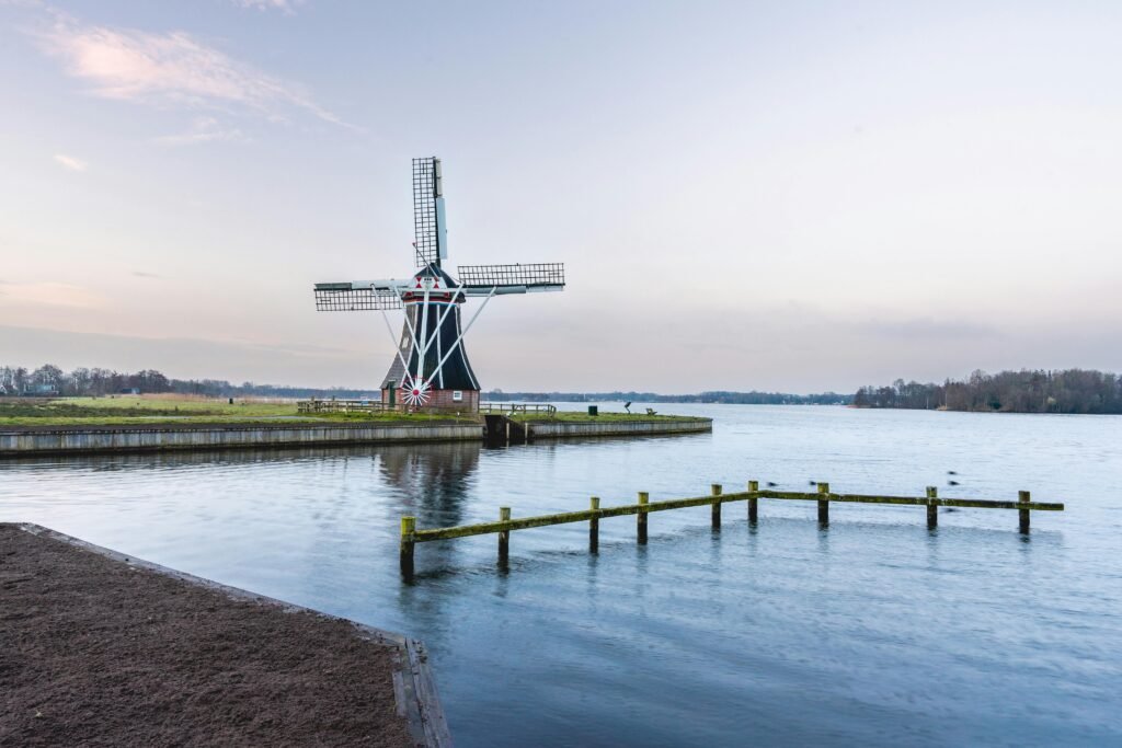 Traditional Dutch windmill reflecting in the calm lake near Haren, Groningen, at dawn.
