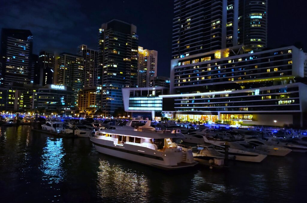 Stunning night view of Dubai Marina with yachts docked and illuminated skyscrapers.