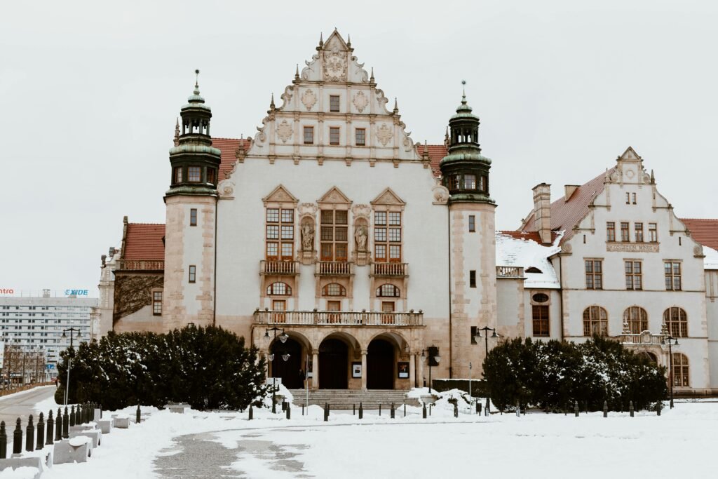 Front view of historic building in Poznań, Poland, with snow-covered surroundings.