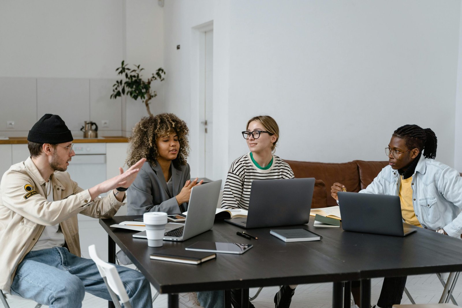 Group of diverse colleagues collaborating with laptops in a modern office setting.