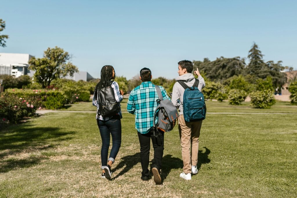 Group of college students walking together outdoors on a sunny day, with backpacks and casual attire.