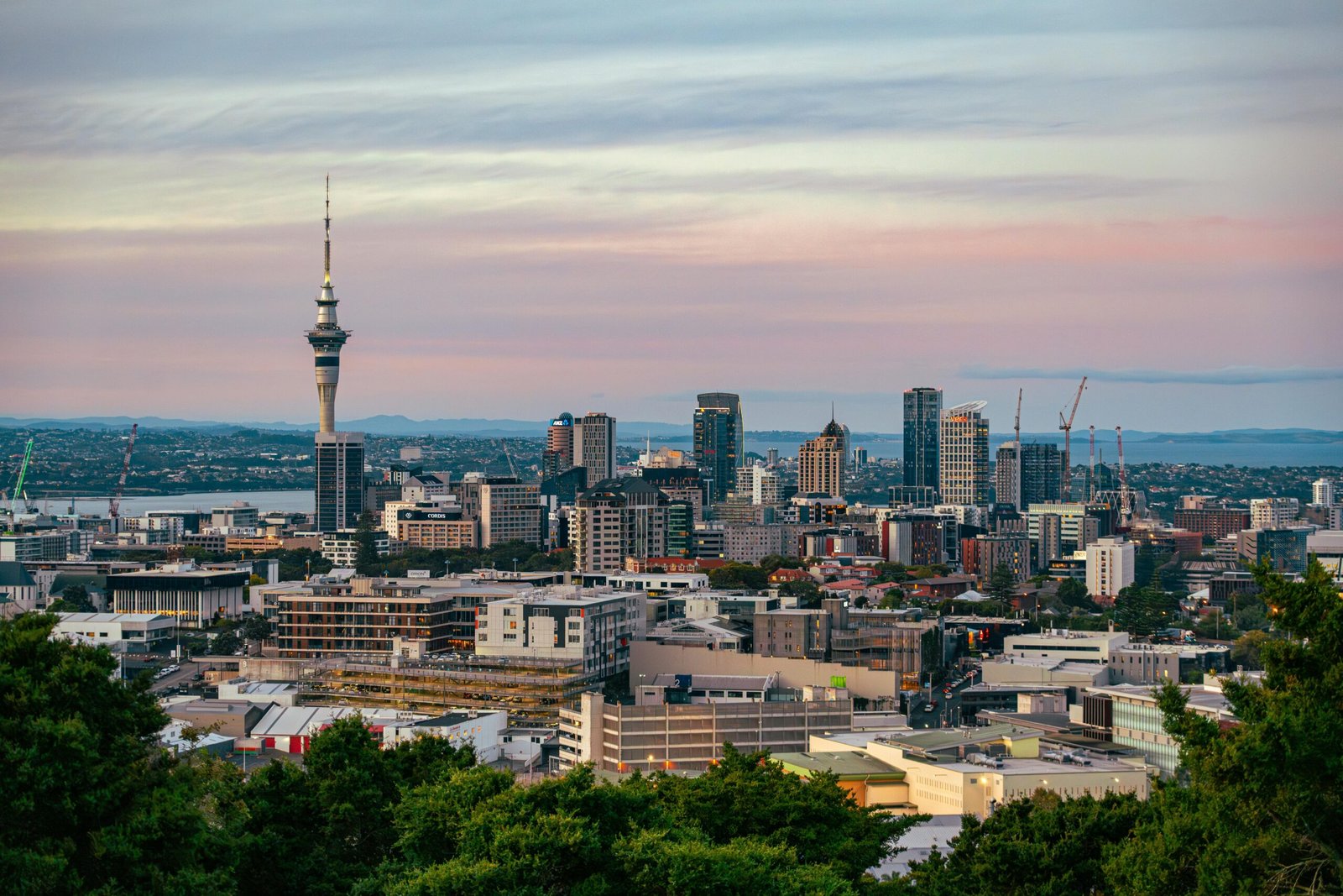 Captivating view of Auckland's skyline at dusk featuring the iconic Sky Tower under a colorful sky.